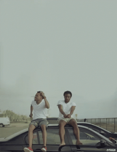 Two Men Are Sitting On The Roof Of A Car With The Letters Steccs On The Bottom Right GIF