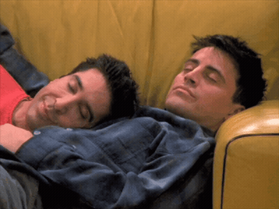 Two Men Are Sleeping On A Yellow Couch GIF