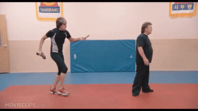 Two Men Are Standing In A Gym With A Sign That Says Samurang On It GIF
