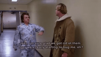 Two Men Are Standing In A Hallway Talking To Each Other And One Of Them Is Wearing Pajamas . GIF