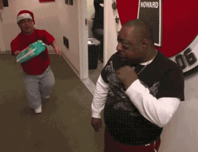 Two Men Are Standing In A Hallway With A Sign That Says Howard GIF