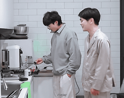 Two Men Are Standing In A Kitchen And One Of Them Has The Word Naughty Written On The Bottom GIF