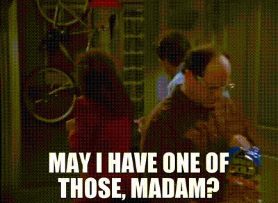 Two Men Are Standing In A Kitchen Talking To Each Other . One Of The Men Is Holding A Bag Of Chips . GIF