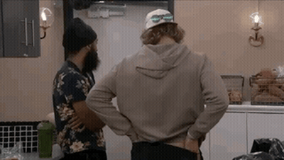 Two Men Are Standing In A Kitchen Talking To Each Other . GIF