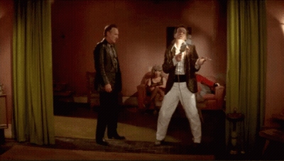 Two Men Are Standing In A Room With A Woman Sitting In A Chair GIF
