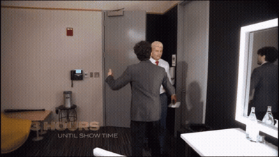 Two Men Are Standing In A Room With The Words 3 Hours Until Show Time On The Wall GIF