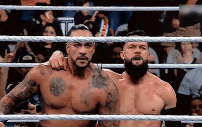 Two Men Are Standing In A Wrestling Ring . GIF