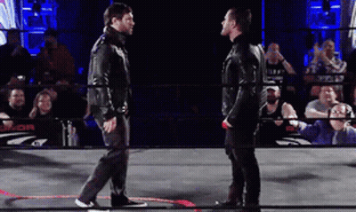 Two Men Are Standing In A Wrestling Ring With A Crowd Behind Them And A Sign That Says J.or. GIF