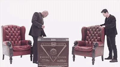 Two Men Are Standing In Front Of A Box That Says Radiola Television GIF