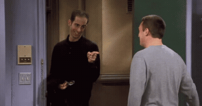 Two Men Are Standing In Front Of A Door And One Is Pointing GIF
