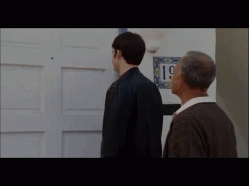 Two Men Are Standing In Front Of A Door With A Sign That Says 19 On It . GIF