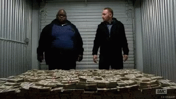 Two Men Are Standing In Front Of A Pile Of Money With A Sign That Says ' A & M ' On It GIF