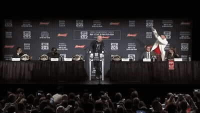 Two Men Are Standing In Front Of A Podium With The Number 205 On It . GIF