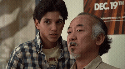 Two Men Are Standing In Front Of A Sign That Says Dec 19Th On It GIF