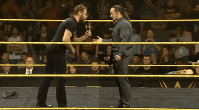 Two Men Are Standing In Front Of A Sign That Says Nk On It GIF