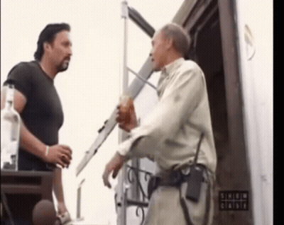 Two Men Are Standing In Front Of A Sign That Says ' Shield ' On It GIF