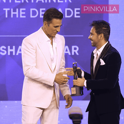 Two Men Are Standing In Front Of A Sign That Says The Decade Pinkvilla GIF