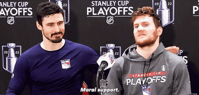 Two Men Are Standing In Front Of A Stanley Cup Playoffs Banner GIF