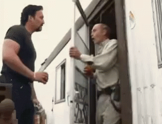 Two Men Are Standing In Front Of A Trailer Talking To Each Other GIF