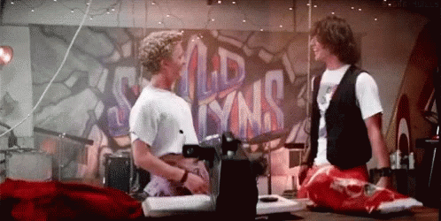 Two Men Are Standing In Front Of A Wall With Graffiti On It . GIF