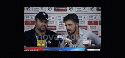 Two Men Are Standing In Front Of Microphones In A Stadium . GIF