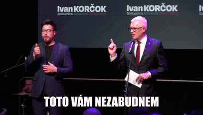Two Men Are Standing In Front Of Microphones With Ivan Korcok Written On The Screen Behind Them GIF
