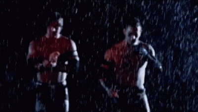 Two Men Are Standing In The Rain Holding Hands And Talking Into Microphones . GIF