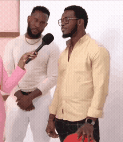 Two Men Are Standing Next To Each Other And A Woman Is Holding A Microphone . One Of The Men Is Wearing Glasses . GIF