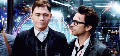 Two Men Are Standing Next To Each Other And Looking At Each Other . One Of The Men Is Wearing Glasses . GIF