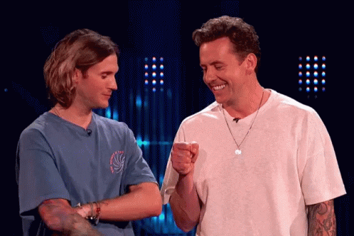 Two Men Are Standing Next To Each Other And One Is Pointing At The Other GIF