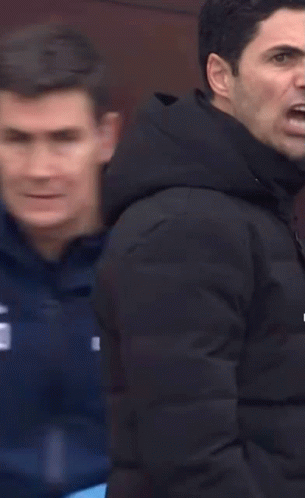 Two Men Are Standing Next To Each Other And One Of Them Is Pointing At The Camera . GIF