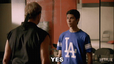 Two Men Are Standing Next To Each Other And One Of Them Is Wearing A La Shirt GIF