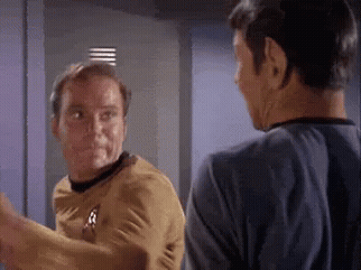 Two Men Are Standing Next To Each Other And Talking In A Room . GIF