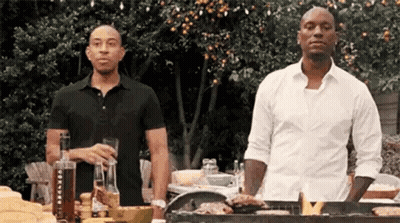 Two Men Are Standing Next To Each Other At A Grill . GIF
