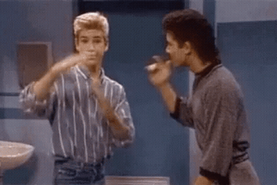 Two Men Are Standing Next To Each Other In A Bathroom . GIF