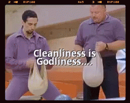 Two Men Are Standing Next To Each Other In A Bowling Alley With The Words Cleanliness Is Godliness Above Them GIF