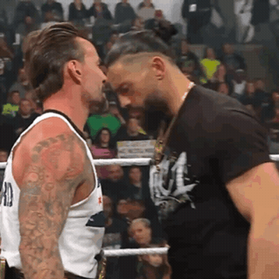 Two Men Are Standing Next To Each Other In A Boxing Ring And Looking At Each Other . GIF