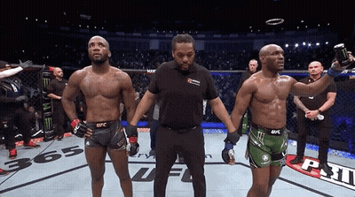 Two Men Are Standing Next To Each Other In A Boxing Ring And One Of Them Is Wearing A Ufc Shorts GIF
