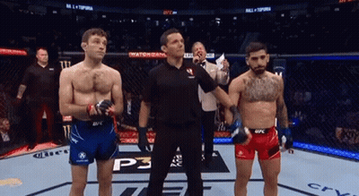 Two Men Are Standing Next To Each Other In A Boxing Ring With A Referee . GIF