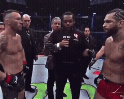 Two Men Are Standing Next To Each Other In A Boxing Ring With A Referee Holding A Microphone . GIF