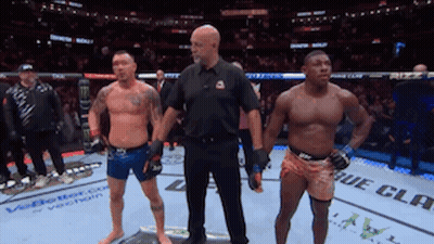 Two Men Are Standing Next To Each Other In A Boxing Ring With A Referee Standing Between Them GIF