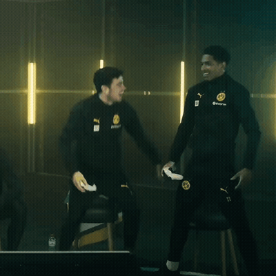 Two Men Are Standing Next To Each Other In A Dark Room And One Of Them Is Holding A Remote Control GIF