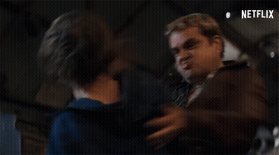 Two Men Are Standing Next To Each Other In A Dark Room And One Of Them Is Making A Funny Face . GIF