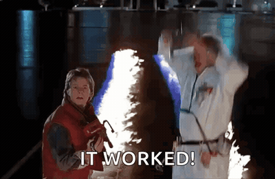 Two Men Are Standing Next To Each Other In A Dark Room With A Flame Coming Out Of Their Hands . GIF