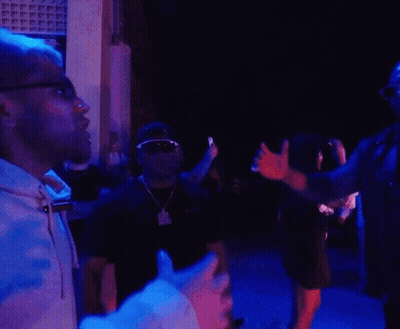 Two Men Are Standing Next To Each Other In A Dark Room With Blue Lights Behind Them GIF