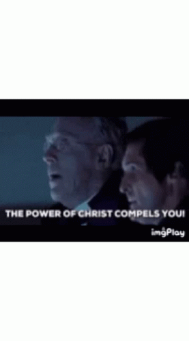 Two Men Are Standing Next To Each Other In A Dark Room With The Words `` The Power Of Christ Compels You '' . GIF