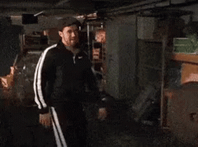 Two Men Are Standing Next To Each Other In A Garage And Talking . GIF