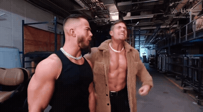 Two Men Are Standing Next To Each Other In A Hallway With A W U X Logo In The Background GIF