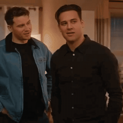 Two Men Are Standing Next To Each Other In A Living Room . One Of The Men Is Wearing A Denim Jacket . GIF