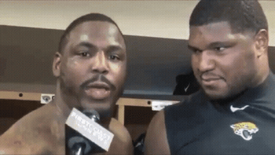Two Men Are Standing Next To Each Other In A Locker Room Talking Into Microphones . GIF